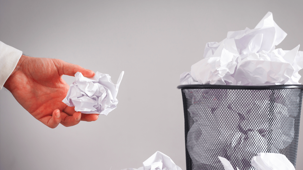 Man throwing balled up paper in trash